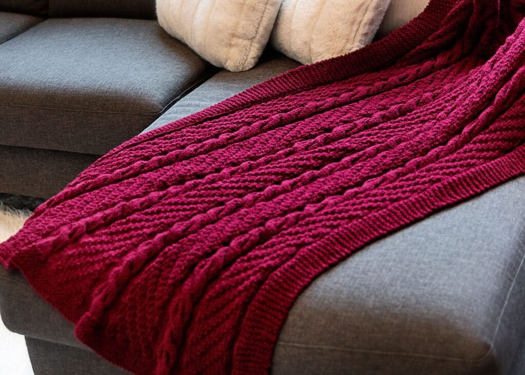 Cozy Cables Throw Blanket knitting pattern - photo of blanket on sofa